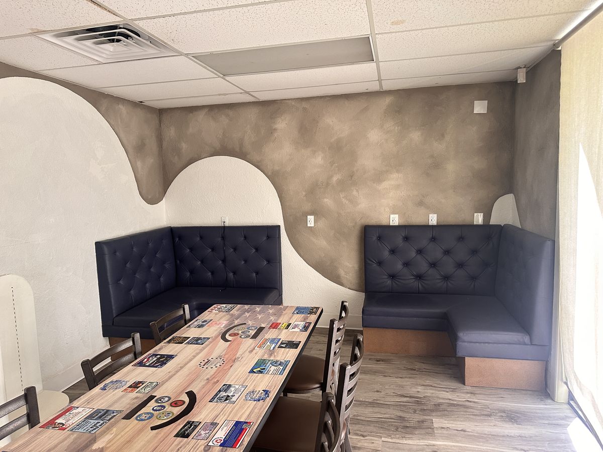 Navy tufted corner booths against a wave-painted wall, with a long wooden table